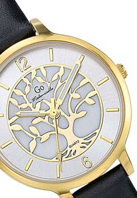 Montre en quartz dorée avec un cadran texturé blanc arborant un motif d'arbre. Bracelet en cuir noir. Les index sont simples et clairs.