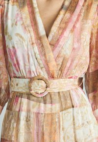 Kleid mit Blumenmuster in sanften Pastellfarben, tiefem V-Ausschnitt und gerafften Ärmeln. Verfügt über einen breiten Gürtel mit einer runden Schnalle.