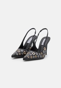 Escarpins à talon aiguille noirs avec bout pointu, ornés d'accents en œillets dorés, argentés et blancs sur le dessus.