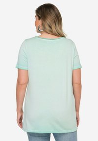 Camiseta de color verde menta claro con mangas cortas, cuello redondo y corte relajado, hecha de suave algodón con una textura lisa.