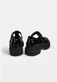 Zwarte gepatineerde leren schoenen met een chunky rubberen zool, enkelband en decoratieve studs langs de achterkant. Rondneus ontwerp.
