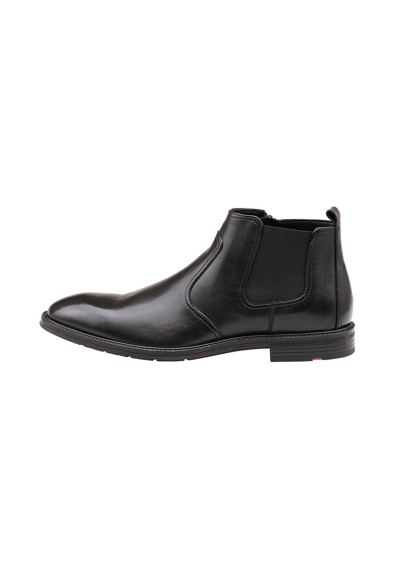 Bottine Chelsea en cuir noir avec une finition lisse, des panneaux élastiques sur les côtés, un bout pointu et une semelle robuste avec un accent rouge sur le talon.