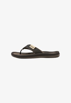 Sandalia de goma negra y marrón tipo chancla con suela texturizada y una tira de tela con una pequeña etiqueta beige.
