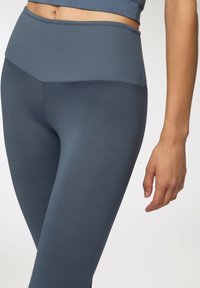 Legginsy o wysokim stanie w matowej, ciemnoniebieskiej tkaninie, z gładkim pasem w talii, charakteryzujące się dopasowanym krojem i minimalną ilością szwów.