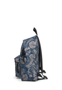 Mochila con tela azul marino y un estampado de hojas tropicales en beige. Vista lateral que muestra correas ajustables y un bolsillo delantero con cremallera.