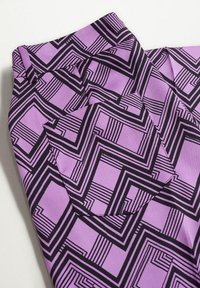 Tissu violet avec un motif géométrique noir composé de lignes et de formes superposées. Comprend un détail de poche intégré dans le design.