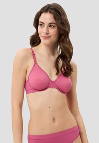 Rosa kabelloser BH mit vorgeformten Cups, verstellbaren Trägern und glatter Textur. Begleitet von passender rosa Unterwäsche.