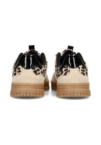 Un paio di sneaker beige con tessuto a stampa leopardata, dettagli in vernice nera sul tallone e suole in gomma spessa marrone, viste da dietro.