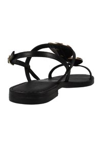 Sandalias de cuero negro con tiras delgadas entrelazadas y suela plana. Acentos dorados notables en la parte superior. Diseño simple con hardware mínimo.