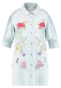 Camicia in denim azzurro chiaro con maniche corte e ricamo floreale in rosa, giallo, bianco e viola. Presenta chiusura con bottoni e tasche laterali.