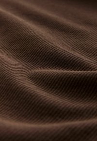 Brown ribbed fabric with a soft texture, showcasing wavy patterns and subtle variations in shade and light across the surface.