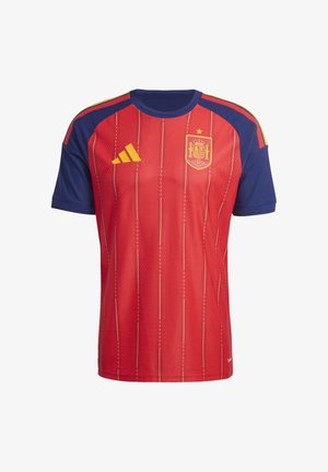 Crvena majica s kratkim rukavima i plavim ramenima, s žutim prugama i grbom. Izrađena je od lagane tkanine s teksturiranim uzorcima.