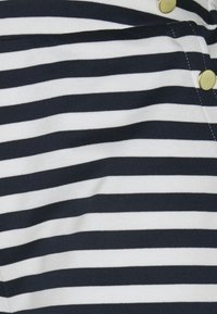 Námornícky modro-bílý pruhovaný materiál s vodorovnými pruhy a zlatými knoflíky. Tkanina se zdá být měkká s hladkým povrchem.