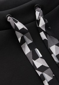 Felpa nera con stringhe grigie e bianche a motivo, caratterizzate da forme poligonali. Texture morbida con una finitura liscia. Due occhielli neri per le stringhe.