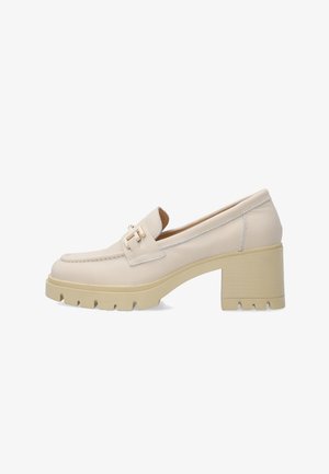Beige leren loafer met chunky blokhak, grof profielzool en decoratieve gouden gesp op het bovendeel, getoond in zijaanzicht op een witte achtergrond.