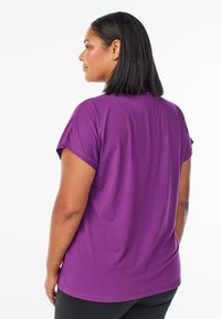 Lila Kurzarm-T-Shirt aus einem weichen, glatten Material. Verfügt über einen runden Ausschnitt und gestickte Säume, entworfen für eine lässige Passform.