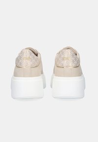 Zapatillas beige con un respaldo texturizado y patternado, suela plataforma blanca y detalles dorados en el talón, con el logo de la marca.