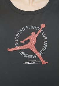 Silhouette d’un joueur de basketball sautant avec un ballon, entourée du texte « Air Jordan Flight Club Official Member » sur un tissu noir.