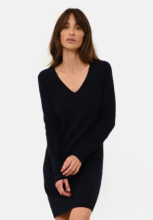 Abito maglione blu navy a V, con maniche lunghe, polsini a costine e vestibilità rilassata. Realizzato in morbido materiale a maglia. Texture liscia.