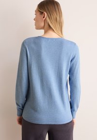 Pull bleu clair à manches longues, col rond, avec des poignets et un ourlet côtelés. Texture douce, conçu pour une coupe décontractée.
