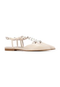 Zapatos planos beige con punteras puntiagudas, correas estructuradas y tachuelas metálicas. Presentan un diseño de talón descubierto y una suela baja de color marrón claro.