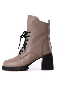Stivale ankle in pelle beige con chiusura nera a lacci, tacco nero chunky, punta arrotondata e suola testurizzata, con dettagli di cucitura visibili.