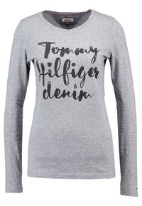 Harmaa pitkähihainen t-paita, joka on valmistettu puuvillasta ja jossa on musta script-teksti "Tommy Hilfiger denim" edessä sekä pyöreä kaula-aukko.