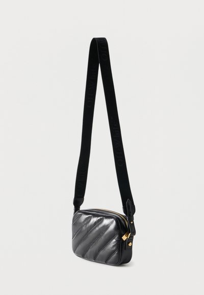 Μαύρη καπιτονέ δερμάτινη τσάντα χιαστί με χρυστό φερμουάρ και ρυθμιζόμενο υφασμάτινο λουράκι με ανάγλυφο λογότυπο.