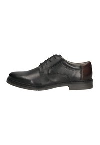 Schwarze Leder-Herrenschuhe mit braunem Absatzakzent, Schnürverschluss und eingeprägtem Markennamen an der Seite.