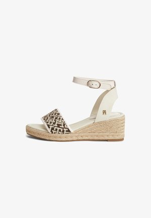 Sandale espadrille compensée avec bride beige à la cheville, bride marron à motif sur les orteils, semelle plateforme en corde tressée et boucle dorée.