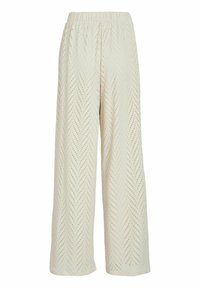 Platas kājas bikses gaiši bēšā krāsā ar teksturētu shevron rakstu un nelieliem caurumiņiem. Elastīga jostasvieta ērtībai.