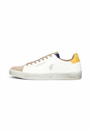 Sneaker bianca bassa con punta beige, lacci marroni, linguetta gialla sul tallone e logo discreto sul lato, su sfondo bianco.