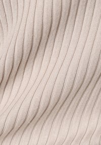 Ribbade tyget i ljus beige, med fina vertikala linjer och en mjuk textur. Materialet ser slätt och flexibelt ut, idealiskt för kläder.