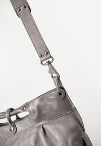 Grijze leren handtas met een gladde textuur. Beschikt over een brede schouderband, metalen hardware en een geplooid ontwerp met een opening aan de bovenkant.