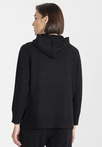 Czarna bluza z kapturem o luźnym kroju, z fakturowanej dzianiny, z prążkowym wykończeniem dołu i rękawów oraz kapturem z tyłu. Czysty, minimalistyczny design.