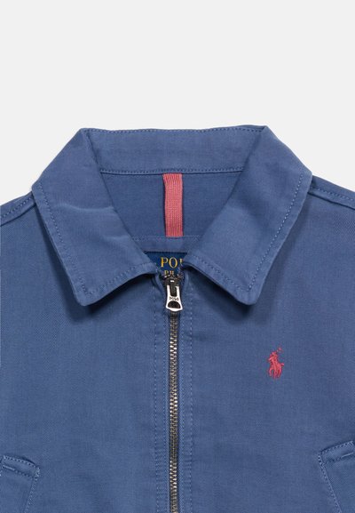 Μπλε μπουφάν με γιακά και εμπρόσθιο φερμουάρ, κόκκινο λογότυπο Polo Ralph Lauren στο στήθος και κόκκινη υφασμάτινη θηλιά μέσα στον γιακά.
