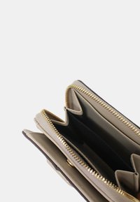 Portafoglio in pelle beige con chiusura a cerniera, dotato di scomparti multipli e superficie testurizzata. Dettagli in metallo color oro.