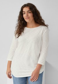 Witte, lichte langemouwen top met een ronde halslijn, zachte textuur en een relaxed fit, gecombineerd met blauwe spijkerbroeken.