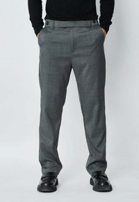 Pantalon gris sur mesure en tissu texturé, doté d'un devant plat, de poches latérales et de deux boutons à la taille.