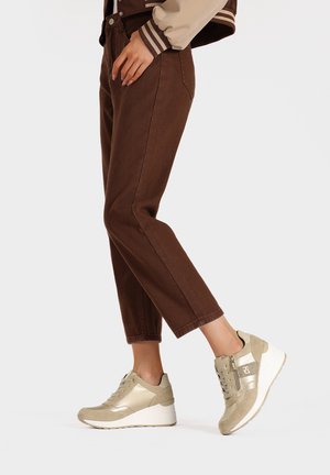 Pantaloni in velluto a coste marroni abbinati a sneaker dorate metallizzate con suola a zeppa, design con lacci e una zip per un tocco di dettaglio in più.