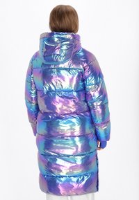 Irideszkáló pufidzseki kapucnival, steppelt textúrával, fémes kék és lila árnyalatokkal, valamint hosszú, oversize sziluettel.