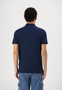 Jūras zils polo krekls, īsas piedurknes, klasiskā apkakle, mīksta kokvilnas auduma, gluda tekstūra, kombinēts ar gaiši ziliem denim šortiem.