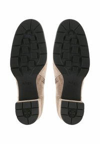 Chaussures en daim avec une tige beige clair et une semelle en caoutchouc noir texturé arborant un motif rectangulaire et un branding subtil sur le talon.