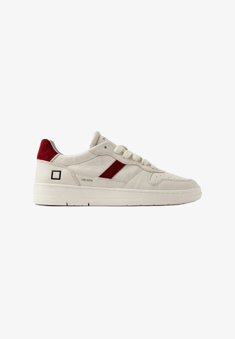 Cremefarvet lædersneaker med en rød ruskindsdetalje, flade snørebånd, perforeret tå og et firkantet logo på siden. Tekstureret hvid sål.