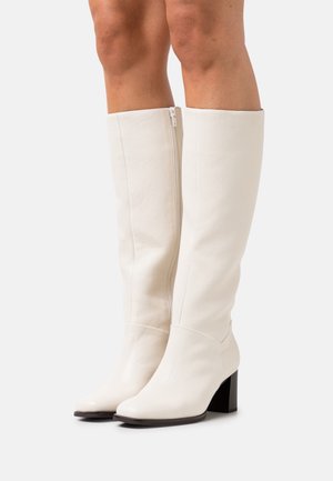 White leather knee-high boots with a sleek design, square toe, and chunky black heel. Features a side zipper for easy wearing.