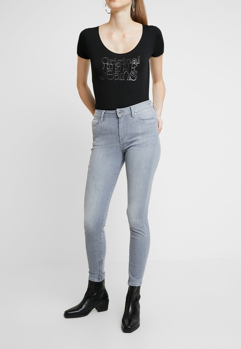 Černý přiléhavý body s logem "Original Pepe Jeans". Světle modré skinny džíny se středně vysokým pasem, hladkou texturou a klasickým pětikapsovým designem.