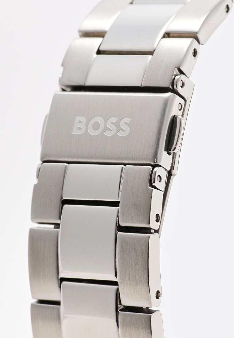 Brazalete de reloj de metal plateado con eslabones pulidos y cepillados, que presenta un cierre marcado con la palabra "BOSS". Eslabones suaves de forma rectangular.