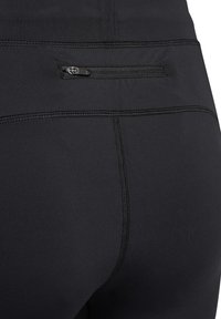 Zwarte sportleggings met een ritssluiting aan de achterkant, een gladde textuur en platlock-naden voor comfort en duurzaamheid.