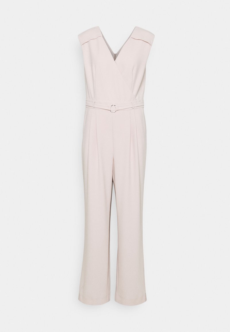 Combinaison beige sans manches avec encolure en V, ceinture avec boucle circulaire à la taille et pantalon à jambes larges.