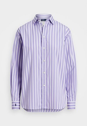 Chemise à manches longues avec boutons, rayée verticalement en blanc et lavande, avec un petit logo brodé sur le poignet gauche.